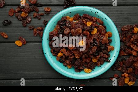 Raisins secs dans la plaque bleue sur fond en bois noir. Vue de dessus Banque D'Images