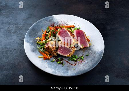 Tataki traditionnel de steak de thon gastronomique japonais avec tranches de légumes et pousses de soja avec sauce douce servie en gros plan sur un motif nordique Banque D'Images