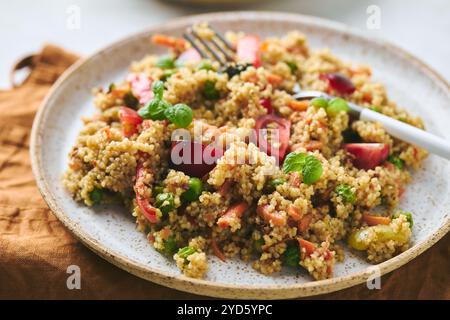 Salade chaude végétalienne à base de couscous, tomates, haricots verts, menthe, carottes rôties et poivrons doux. Couscous avec des légumes dans un bol sur backgro léger Banque D'Images