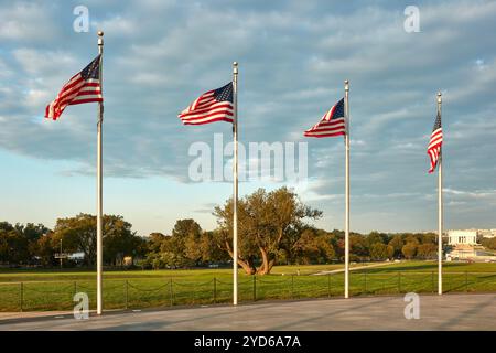 Une rangée de quatre drapeaux américains se dresse haut, agitant gracieusement dans la brise du soir sur fond d'un ciel partiellement nuageux. Les drapeaux sont positionnés en i. Banque D'Images
