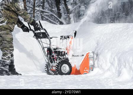 Souffleuse automotrice pour chasse-neige. L'homme en gants de vêtements chauds au lieu de la grande pelle a choisi un engi automoteur Banque D'Images