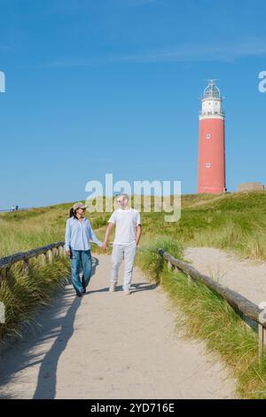 Un couple se promène tranquillement le long d'un chemin près d'un phare pittoresque à Texel, pays-Bas, en profitant des vues panoramiques et chacun ot Banque D'Images