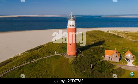 Une vue aérienne à couper le souffle d'un phare imposant debout sur les rives sablonneuses de Texel, pays-Bas, guidant les navires safel Banque D'Images