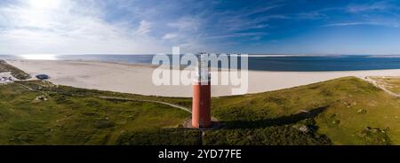 Une vue d'oeil d'oiseau d'un grand phare Texel avec un phare brillant brillamment sur une plage de sable, surplombant le vaste océan sur le i. Banque D'Images