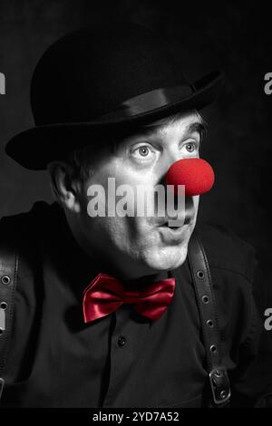 Portrait couleur sélectif dramatique d'un clown surpris sur un fond sombre. Banque D'Images