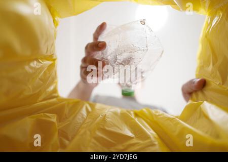 Image de l'intérieur du sac de recyclage jaune d'un homme jetant une bouteille en plastique vide dans un bac de recyclage Home recycle éco vert zéro concept Banque D'Images