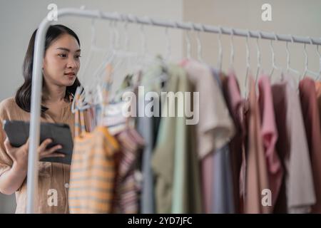 Femme asiatique tenant la tablette numérique dans le petit magasin de tissu magasin en ligne vente ou e-commerce Banque D'Images