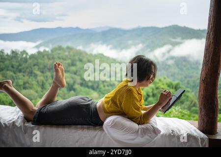 Femme asiatique voyageur freelance travaillant en ligne à l'aide de la tablette. penser idée créative dans le matin de la montagne de falaise de la nature. Banque D'Images