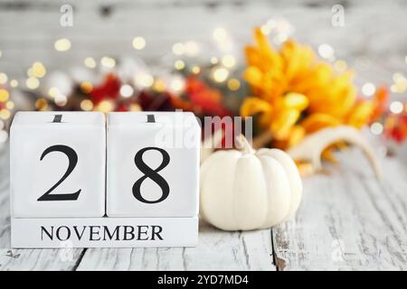 Blocs de calendrier en bois blanc avec date du 28 novembre et décorations d'automne sur une table en bois. Mise au point sélective avec arrière-plan flou. Banque D'Images