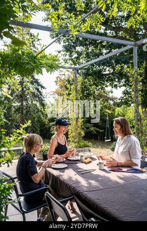 Femme et adolescents assis à table sur la terrasse d'une villa de luxe dans le sud de la France. Banque D'Images