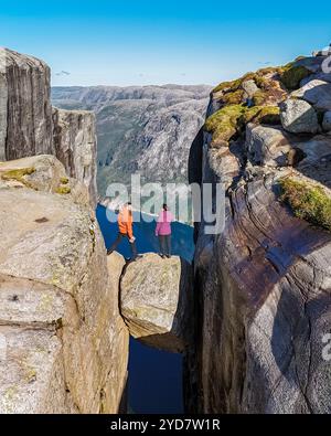 Deux personnes se tiennent sur le bord de Kjeragbolten Pulpit Rock en Norvège, donnant sur la vallée à couper le souffle ci-dessous Banque D'Images