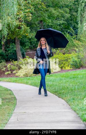 Glimmers in the Gloom : a Woman's graceful Dance with the Rain Banque D'Images