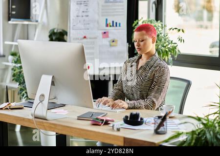 Une femme chauve avec une couleur de cheveux vibrante se concentre sur le travail à un bureau élégant au milieu de la verdure. Banque D'Images