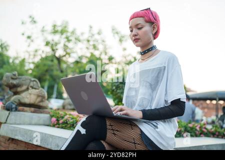 Gen z fille mode en cuir avec femme asiatique punk travaillant à distance sur ordinateur portable nomade numérique en Thaïlande Banque D'Images