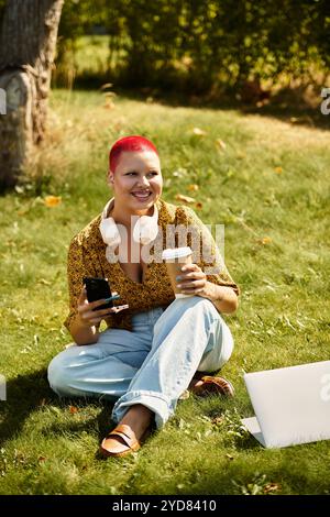 Une joyeuse femme chauve se détend dans la nature, sirotant un café et utilisant son téléphone, entourée de verdure. Banque D'Images