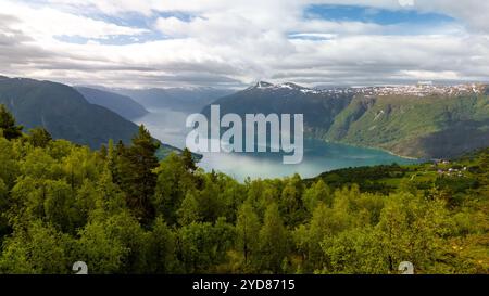 Une vue imprenable sur un fjord norvégien, entouré de forêts verdoyantes et de montagnes enneigées, sous un ciel nuageux. Randonnée Molden, Norvège Banque D'Images