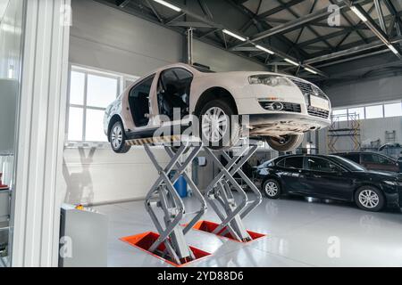 Voiture sur le relevage hydraulique à l'atelier de réparation automobile. Service automatique Banque D'Images