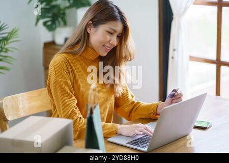 Femme shoppingÂ sur l'ordinateur portable tenant la carte de crédit pour Internet en ligne e-commerce shopping dépenser de l'argent en ligne achats Mobile phon Banque D'Images