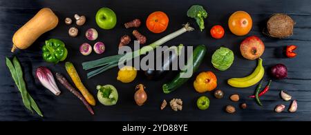 Plan panoramique de fruits et légumes frais déposés en vrac sur une table en bois noir. Banque D'Images