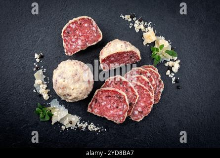 Salami traditionnel italien saltufo enrobé de parmesan et truffe servi comme vue de dessus sur un plateau design noir Banque D'Images