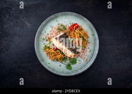 Filet de cabillaud skrei frit avec salade de som tam de papaye et riz rouge servi comme vue de dessus sur une assiette au design nordique avec espace copie Banque D'Images