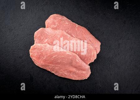 Filets d'escalope de poulet crus traditionnels offerts comme vue de dessus sur un tableau noir avec espace de copie Banque D'Images