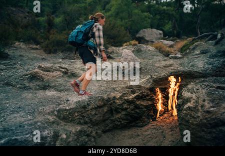 Backpacker femme randonnée seul le long des feux de Yanartas la nuit sur le mont Chimaera sur la randonnée populaire Lycian Way (Likya Yolu) dans la province d'Antalya, Turquie Banque D'Images