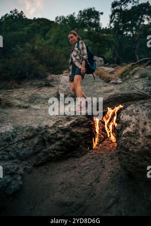 Backpacker femme randonnée seul le long des feux de Yanartas la nuit sur le mont Chimaera sur la randonnée populaire Lycian Way (Likya Yolu) dans la province d'Antalya, Turquie Banque D'Images