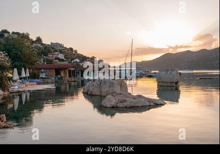 Sarcophage de pierre et falaises ont prêté la lumière du matin à Simena Kaleköy ville Turquie submergée dans les eaux claires de la Méditerranée entourée de collines escarpées. Banque D'Images