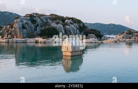 Sarcophage en pierre de l'ancienne ville de Simena Kaleköy Turquie, se trouve partiellement submergé dans les eaux claires de la Méditerranée entouré de collines escarpées répertoriées Banque D'Images