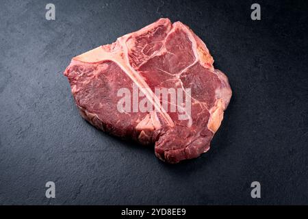 Steak de bœuf chianina vieilli cru et sec offert en gros plan sur une vieille planche rustique Banque D'Images