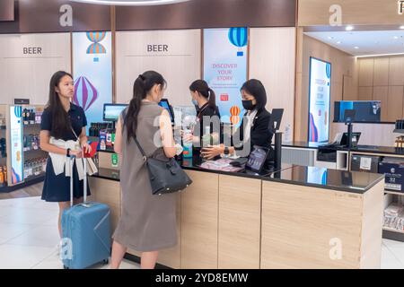 Terminal 4 de l'aéroport Changi de Singapour, boutique hors taxes, guichet de départ, femmes payant pour des boissons alcoolisées au guichet de départ Banque D'Images