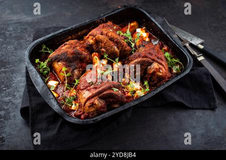 Jarret d'agneau braisé traditionnel cuit lentement avec aubergines et fromage feta grec servi en gros plan sur une cocotte rustique avec c Banque D'Images