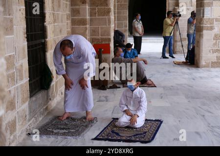 Gaza, Palestine. 22 mai 2020. Les fidèles qui assistent aux prières du vendredi donnent des masques de protection à l’entrée d’une mosquée dans la ville de Gaza. Les autorités de Gaza ont autorisé la réouverture des mosquées pour les prières du vendredi dernier avant la fin du Ramadan, après les avoir maintenues fermées depuis mars pour contenir la propagation du coronavirus. Environ 35 nouveaux cas ont été isolés ces derniers jours à la suite du retour de Palestiniens à Gaza depuis l’Égypte et Israël, portant le nombre total d’infections à COVID-19 à 55. Bien que les nouveaux cas aient été détectés dans des installations de quarantaine, les autorités restent vigilantes Banque D'Images