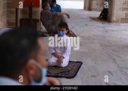 Gaza, Palestine. 22 mai 2020. Les fidèles qui assistent aux prières du vendredi donnent des masques de protection à l’entrée d’une mosquée dans la ville de Gaza. Les autorités de Gaza ont autorisé la réouverture des mosquées pour les prières du vendredi dernier avant la fin du Ramadan, après les avoir maintenues fermées depuis mars pour contenir la propagation du coronavirus. Environ 35 nouveaux cas ont été isolés ces derniers jours à la suite du retour de Palestiniens à Gaza depuis l’Égypte et Israël, portant le nombre total d’infections à COVID-19 à 55. Bien que les nouveaux cas aient été détectés dans des installations de quarantaine, les autorités restent vigilantes Banque D'Images