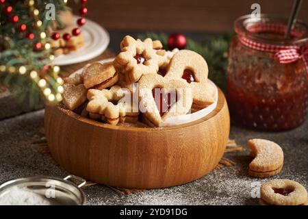 Biscuits de Noël Linzer maison remplis de confiture de fraises et saupoudrés de sucre dans un bol en bois sur une table Banque D'Images