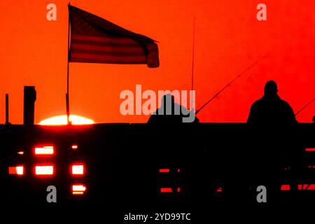 Île de Palms, États-Unis. 25 octobre 2024. Pêcheurs silhouettés par le lever du soleil, regardez le soleil orange géant se lever sur l'océan Atlantique depuis l'embarcadère de l'île de Palms sur Front Beach, le 25 octobre 2024 à l'île de Palms, Caroline du Sud. Un temps ensoleillé et chaud est prévu pour le pays bas pour les prochaines semaines. Crédit : Richard Ellis/Richard Ellis/Alamy Live News Banque D'Images