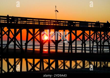 Île de Palms, États-Unis. 24 octobre 2024. Touristes silhouettés par le lever du soleil, regardez le soleil orange géant se lever sur l'océan Atlantique depuis l'embarcadère de l'île de Palms sur Front Beach, le 24 octobre 2024 à l'île de Palms, Caroline du Sud. Un temps ensoleillé et chaud est prévu pour le pays bas pour les prochaines semaines. Crédit : Richard Ellis/Richard Ellis/Alamy Live News Banque D'Images