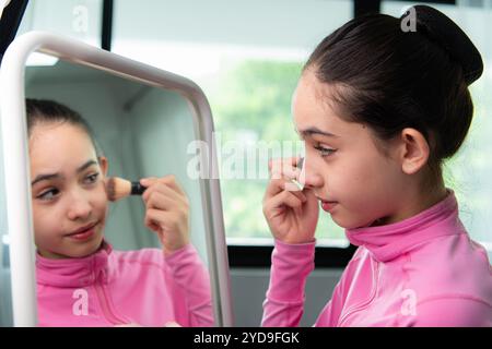 Une étudiante de ballet fille en survêtement rose utilise le blush pour se maquiller avant d'effectuer le ballet Banque D'Images