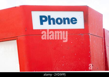 Cabine téléphonique rouge avec un panneau blanc qui dit « téléphone ». Le stand est situé dans un parking Banque D'Images