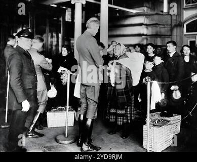 Médecins du service de santé publique vérifiant les immigrants arrivant aux États-Unis pour des signes de maladie. La loi sur l'immigration de 1891 a rendu obligatoire que tous les immigrants arrivant aux États-Unis se soumettent à une inspection sanitaire par des médecins du Service de santé publique. Le plus grand centre d'inspection était sur Ellis Island dans le port de New York. Sur cette photo de 1910, les médecins regardent les yeux pour déceler des signes de trachome. Ellis Island public Health Service Physicians 016867 188 Banque D'Images