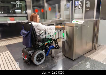 Femme en fauteuil roulant en utilisant l'entrée accessible au métro Banque D'Images