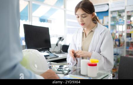 Le pharmacien fournit des médicaments aux ingénieurs qui viennent acheter des médicaments dans la pharmacie. Banque D'Images