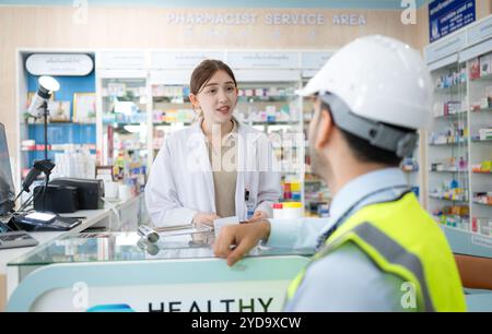 Le pharmacien fournit des médicaments aux ingénieurs qui viennent acheter des médicaments dans la pharmacie. Banque D'Images