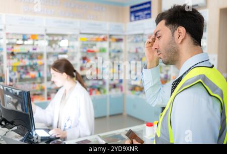 Le pharmacien fournit des médicaments aux ingénieurs qui viennent acheter des médicaments dans la pharmacie. Banque D'Images