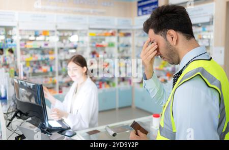 Le pharmacien fournit des médicaments aux ingénieurs qui viennent acheter des médicaments dans la pharmacie. Banque D'Images