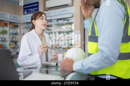 Le pharmacien fournit des médicaments aux ingénieurs qui viennent acheter des médicaments dans la pharmacie. Banque D'Images