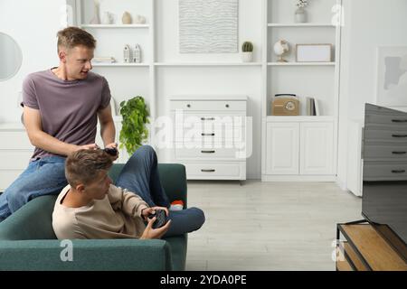 Jeunes frères jouant au jeu vidéo sur canapé à la maison Banque D'Images
