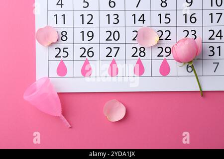 Composition plate de pose avec calendrier et coupe menstruelle sur fond rose Banque D'Images