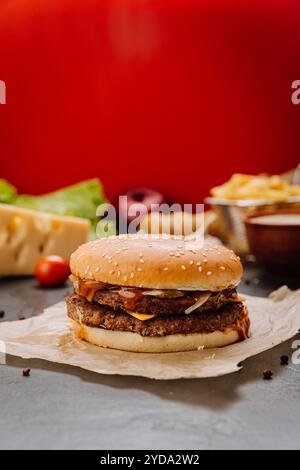 Double cheeseburger avec fromage fondu, cornichons et sauce barbecue sur un pain au sésame. Photographie culinaire Banque D'Images